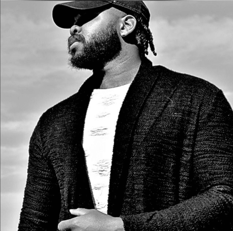 Stylish man in sunglasses and cap looking into the distance.
